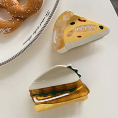 overhead view of acrylic slice of pizza hair clip and sandwich hair clip on a white surface next to pretzels