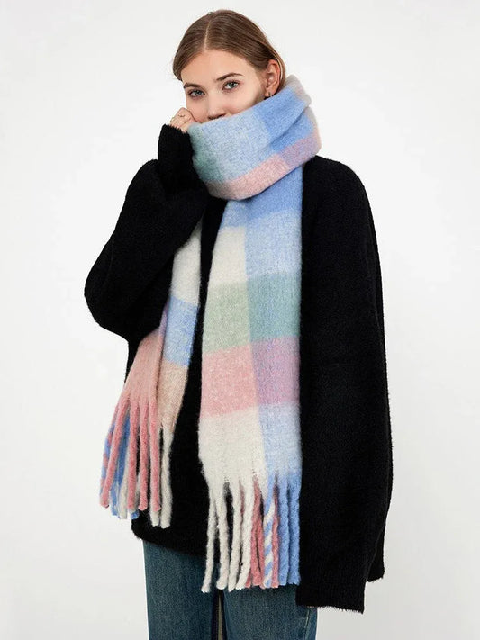 Woman wearing a black sweater and a pastel plaid scarf with fringe.