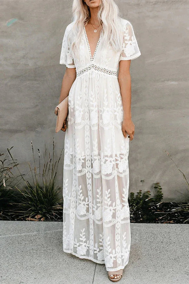 woman in a white lace maxi dress with blonde hair, holding a light-colored clutch