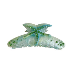 Close-up of a blue and white marbled resin hair claw clip shaped like a starfish, adorned with green rhinestones.
