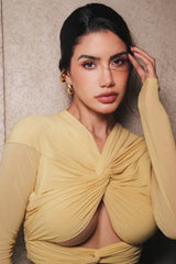 Close-up of a woman wearing a yellow ruched jersey top with a twisted front and plunging neckline