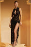 Woman wearing a black lace maxi dress with a high neckline and thigh-high slit, holding a clutch.