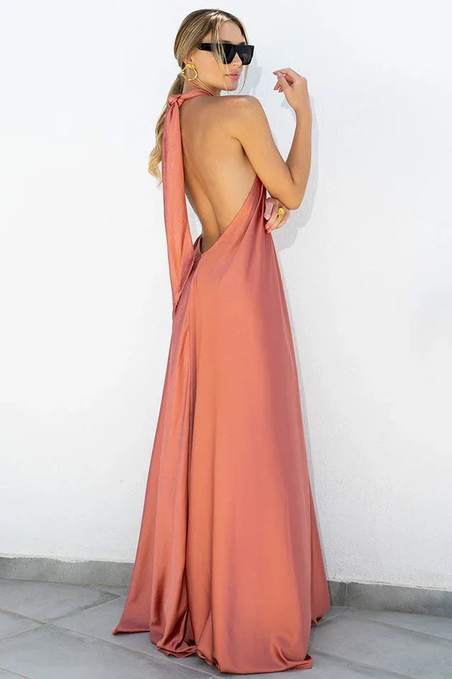 Back view of a woman in a coral satin halter maxi dress with an open back.