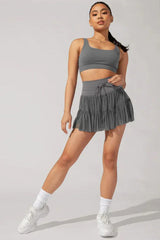 Woman in grey sports bra and ruffled tulle skirt posing