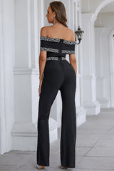 Back view of a woman in a black off-the-shoulder jumpsuit with geometric trim.