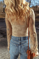 Back view of a woman wearing a tan lace long-sleeved top with a scoop neckline and bell sleeves, paired with blue denim jeans.