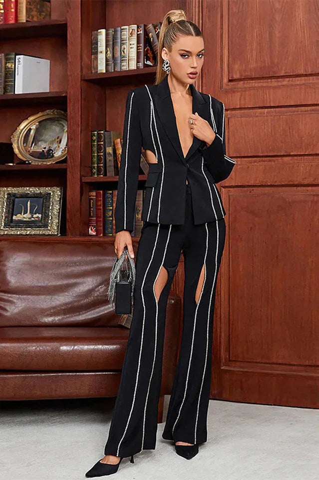 Woman in a black suit with cut-out details and decorative trim, standing in a library setting.