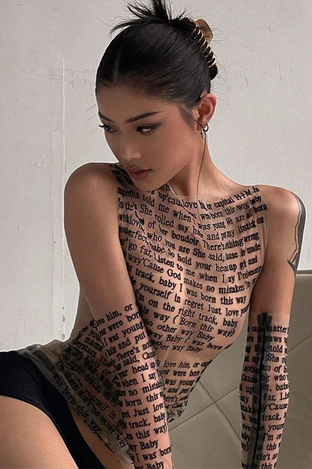 Woman in a sheer black top with text print, looking down.
