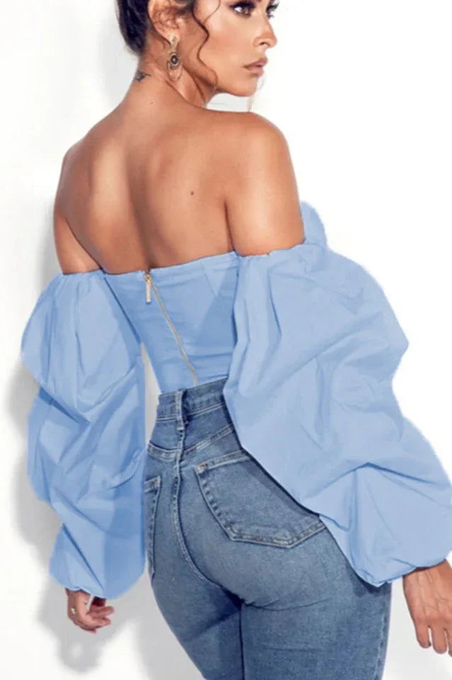 Woman wearing a light blue off-the-shoulder crop top with puff sleeves and blue jeans, back view