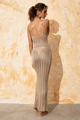 Back view of a woman wearing a beige knit maxi dress with spaghetti straps, showcasing the sheer knit pattern.
