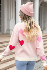 Rear view of a woman wearing a pink heart print sweater and a pink beanie, showing the heart print on the back.