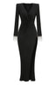 Full-length studio shot of a long-sleeved black jersey knit gown with a plunging V-neckline, ruched bodice, thigh-high slit, and embellished cuffs.