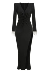 Full-length studio shot of a long-sleeved black jersey knit gown with a plunging V-neckline, ruched bodice, thigh-high slit, and embellished cuffs.