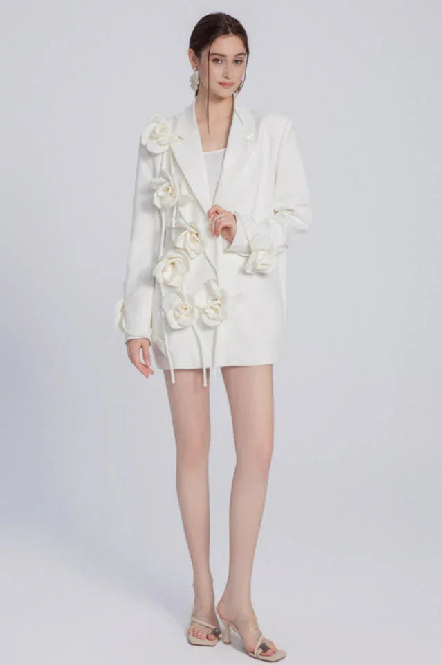 Model showcasing a white blazer dress with intricate floral details