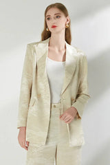 Woman with gold earrings wearing a cream jacquard suit.