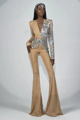 Full-length view of a woman in a tan and silver sequined jumpsuit with a dramatic V-neck and flared trousers.