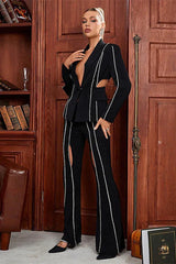 Woman in a black suit with cut-out details and decorative trim, adjusting her blazer.