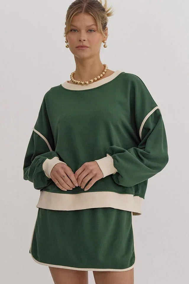 Woman wearing a green crew neck sweatshirt with cream trim and matching shorts