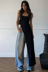 Woman wearing a black sleeveless maxi dress with a high slit over light blue wide-leg jeans indoors