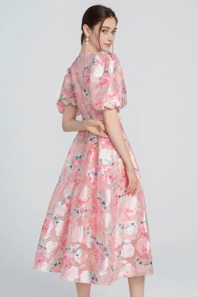 Back view of a woman in a pink floral jacquard dress.