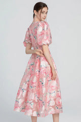Back view of a woman in a pink floral jacquard dress.