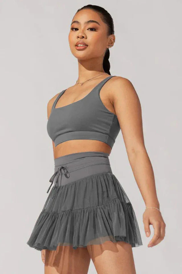 Woman in grey sports bra and ruffled tulle skirt