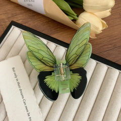 Green butterfly hair claw clip on a textured surface