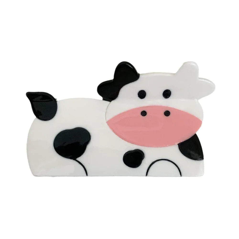 A cute cow-shaped hair clip with black and white spots and a pink muzzle.