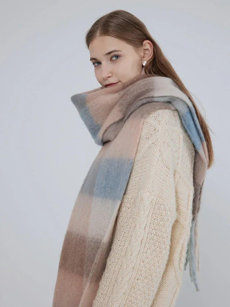 Close-up of a woman wearing a cream cable knit sweater and a plaid scarf.