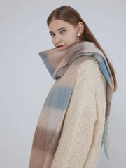 Close-up of a woman wearing a cream cable knit sweater and a plaid scarf.