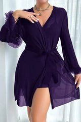 Woman wearing a purple sheer robe with ruffled cuffs and a tie waist