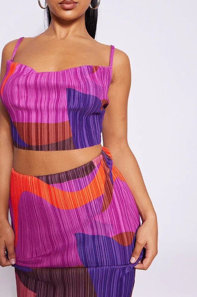 Detail of a woman's torso wearing a matching abstract print pleated crop top and maxi skirt.