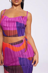 Detail of a woman's torso wearing a matching abstract print pleated crop top and maxi skirt.