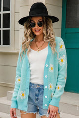 Woman wearing a light blue daisy print knit cardigan with denim shorts and sunglasses