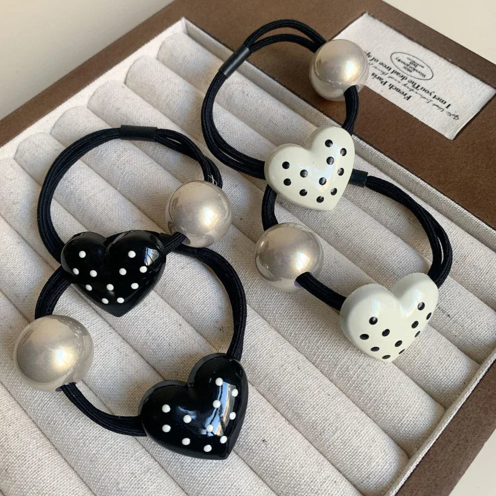 Set of heart-shaped hair ties, some white and some black, with silver beads