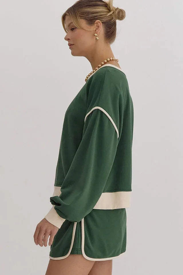 Side view of a woman in a green sweatshirt with cream trim
