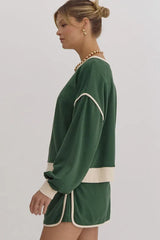Side view of a woman in a green sweatshirt with cream trim