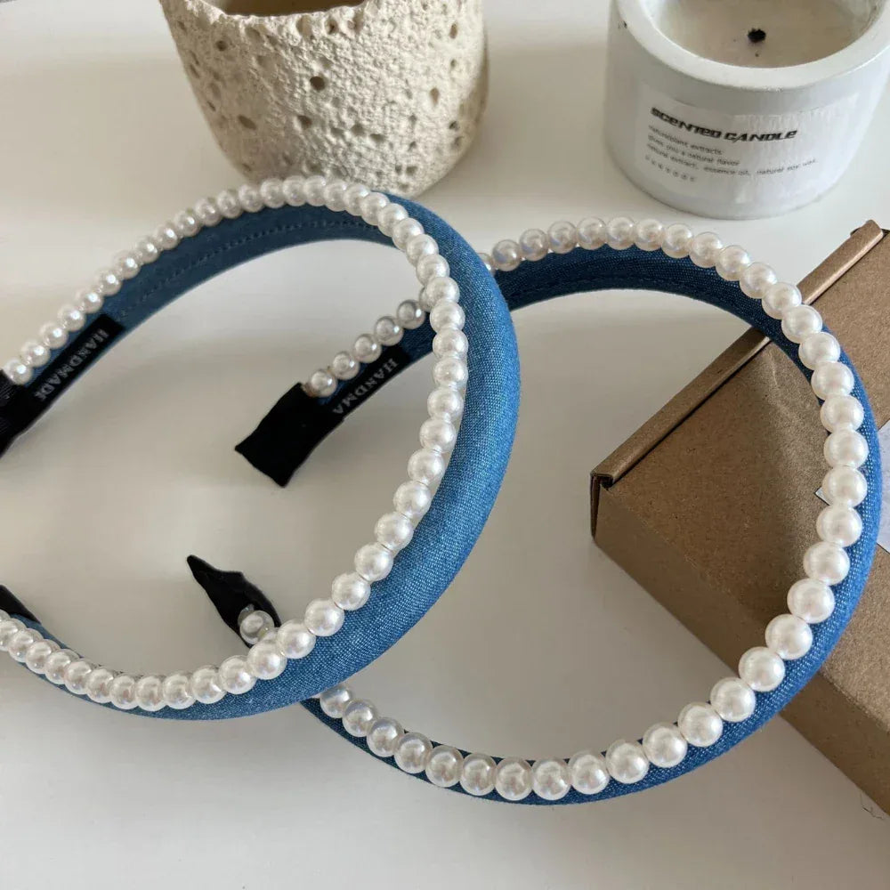 Two blue denim headbands with pearl trim arranged on a table