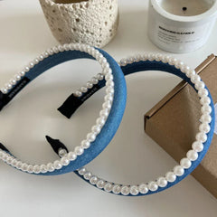Two blue denim headbands with pearl trim arranged on a table