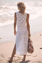 back view of a woman wearing a white crochet knit midi dress with side slits on the beach