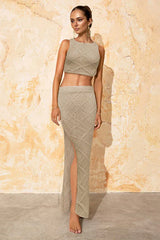 Woman wearing a beige knit crop top and maxi skirt with a high slit, posing