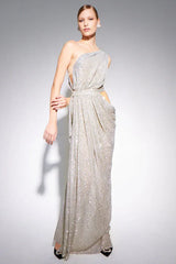Model wearing a silver sequined one-shoulder draped gown with cut-out waist