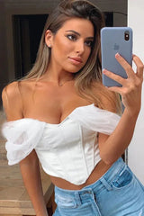 Woman taking a selfie in a white off-the-shoulder corset top and blue jeans