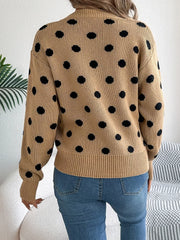Woman wearing a brown polka dot sweater with blue jeans, back view.