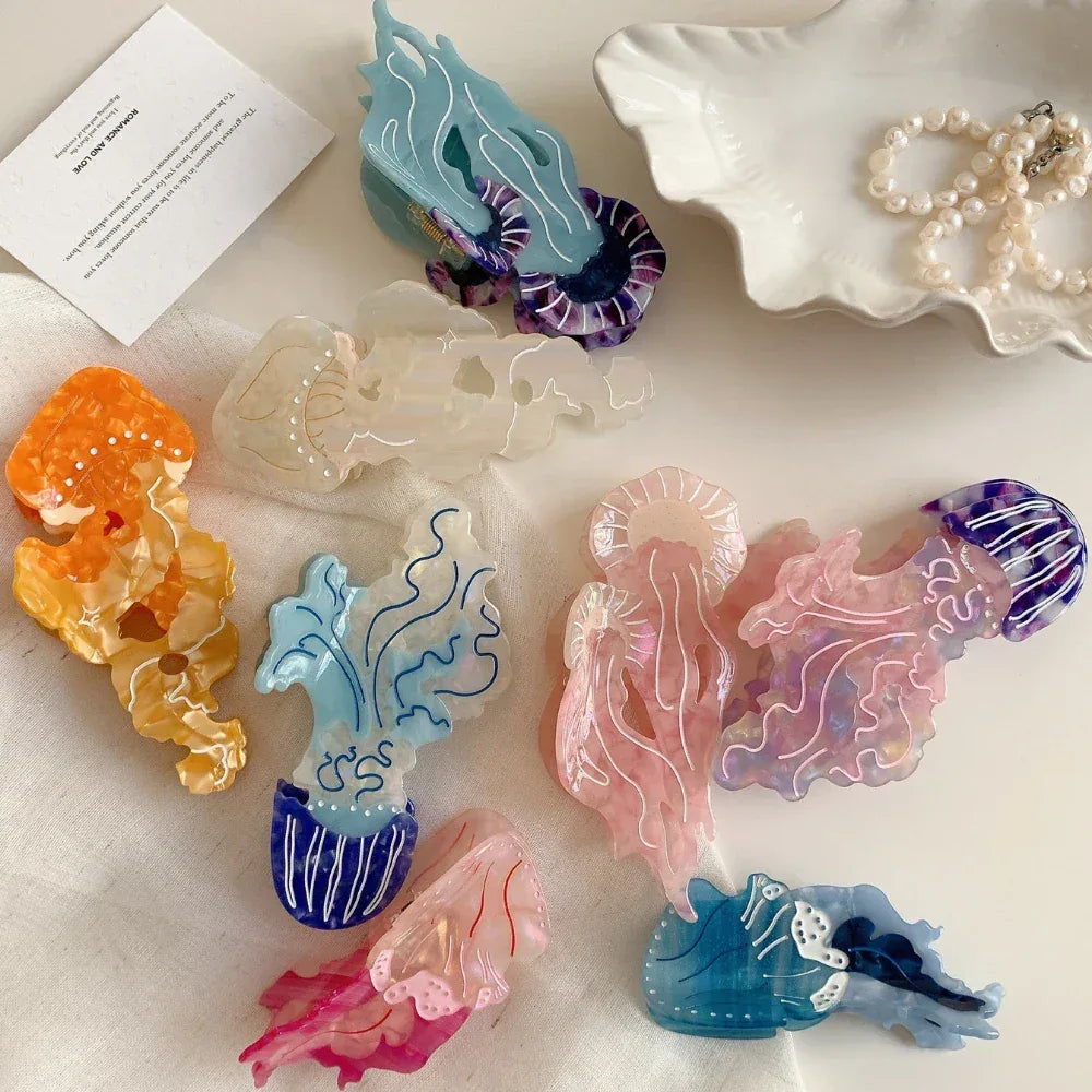 Collection of colorful acrylic jellyfish hair clips in various sizes and colors, including pink, blue, orange, and white, scattered on a white surface.