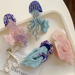 Four acrylic jellyfish hair clips, including pink, purple, blue, and light pink, arranged on a white tray with a pearl necklace.