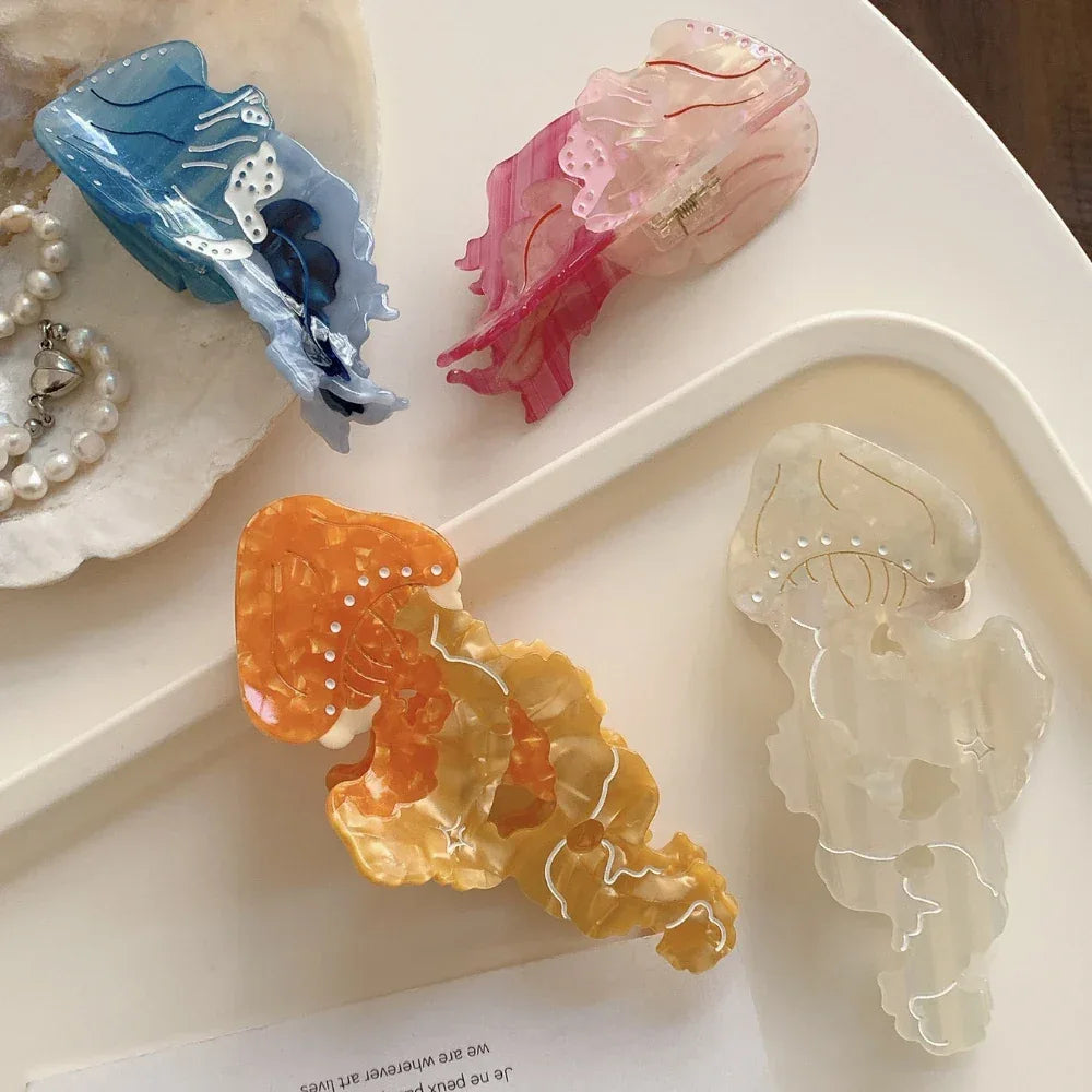 Close-up of acrylic jellyfish hair clips in blue, pink, orange, and white, displayed on a white tray.