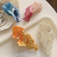 Close-up of acrylic jellyfish hair clips in blue, pink, orange, and white, displayed on a white tray.