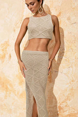 Close-up of a woman wearing a beige knit crop top and maxi skirt with a high slit
