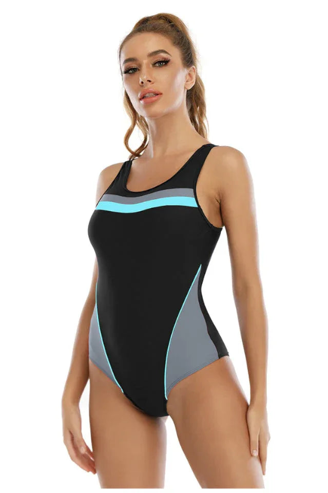 Woman wearing a black one-piece swimsuit with grey and blue color blocking